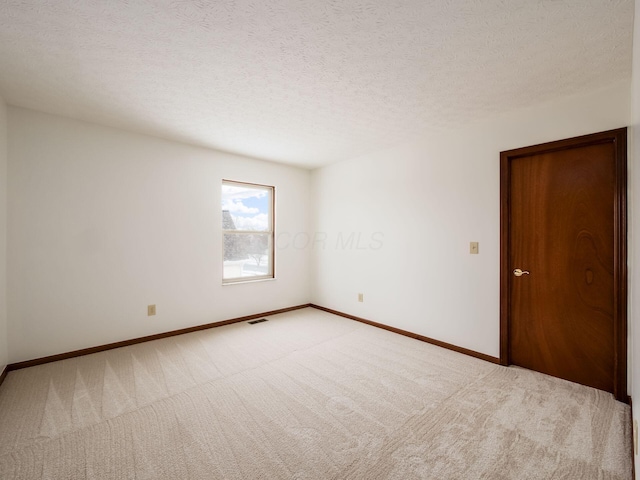 spare room featuring baseboards, visible vents, a textured ceiling, and carpet flooring