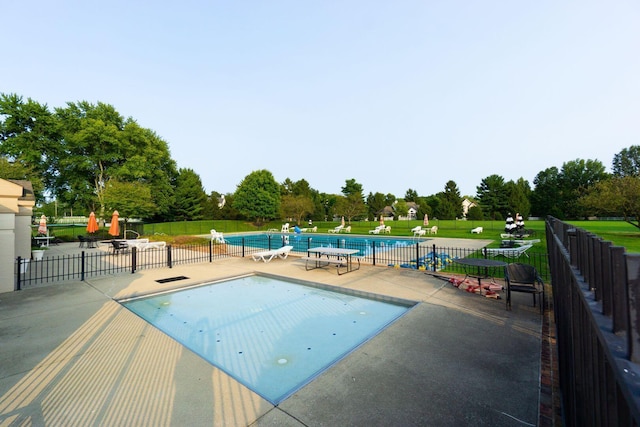 community pool featuring a patio, a lawn, and fence