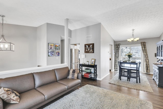 living room with dark wood finished floors, visible vents, an inviting chandelier, vaulted ceiling, and a textured ceiling