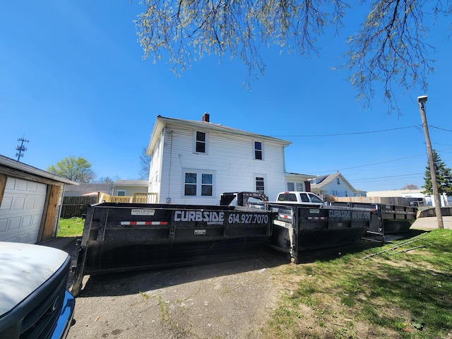 rear view of property featuring a chimney and fence