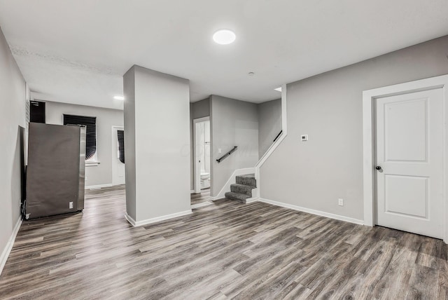 below grade area with baseboards, stairway, and wood finished floors