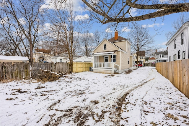 snow covered rear of property with a chimney, fence, and a residential view