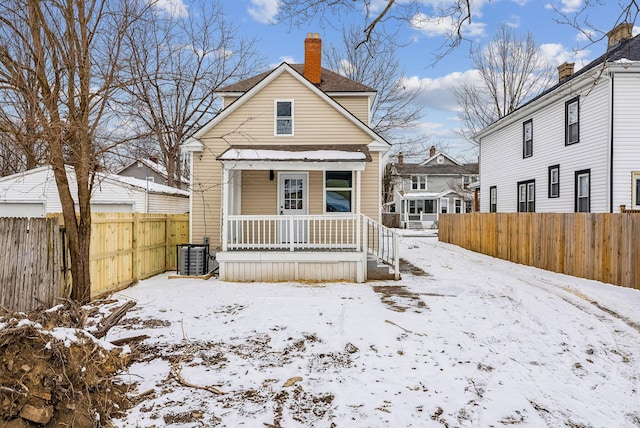 view of front of house featuring covered porch, a chimney, fence, and central AC