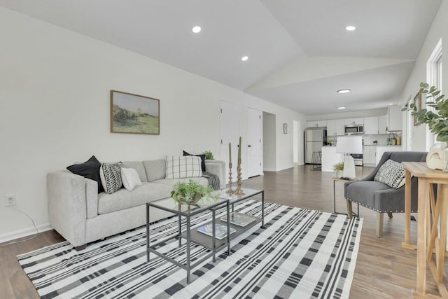 living area featuring baseboards, recessed lighting, lofted ceiling, and light wood finished floors