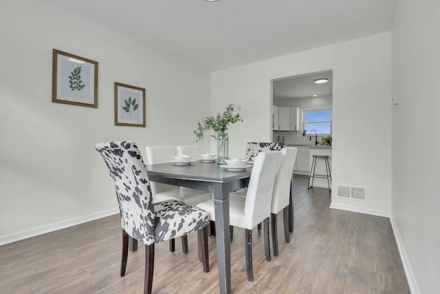 dining space featuring visible vents, baseboards, and wood finished floors