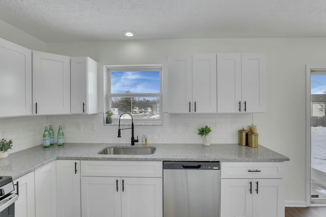 kitchen with a sink, backsplash, white cabinetry, and stainless steel appliances