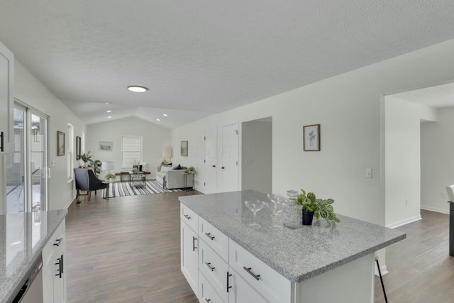 kitchen with light stone counters, open floor plan, and white cabinetry