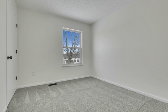 empty room featuring baseboards, visible vents, carpet flooring, and a textured ceiling