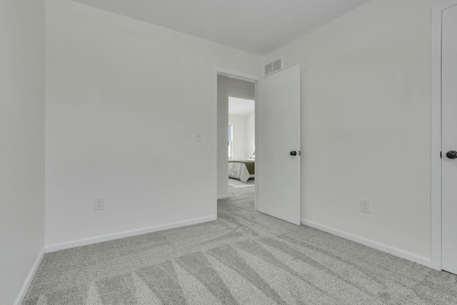 spare room featuring visible vents, baseboards, and light colored carpet