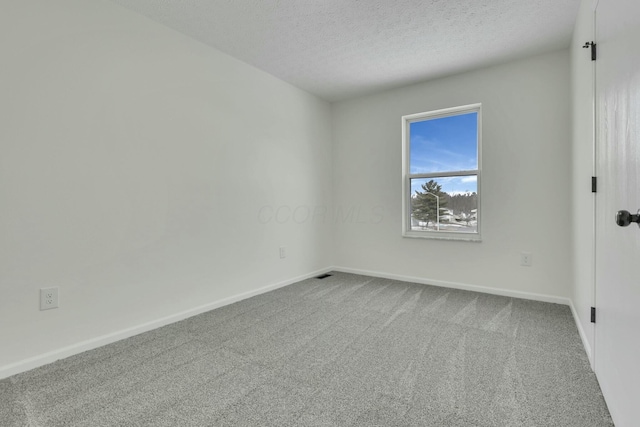 unfurnished room with a textured ceiling, visible vents, baseboards, and carpet floors