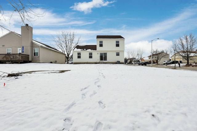 snow covered back of property featuring a residential view and a wooden deck