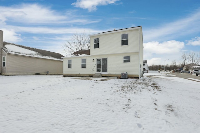 snow covered rear of property with central AC unit