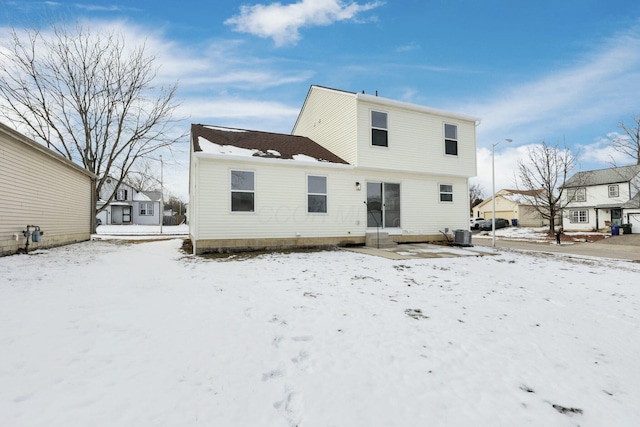 snow covered house featuring central AC unit