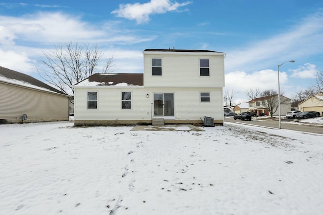 snow covered back of property featuring central air condition unit and entry steps