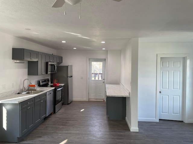 kitchen with gray cabinetry, light countertops, a sink, and stainless steel appliances