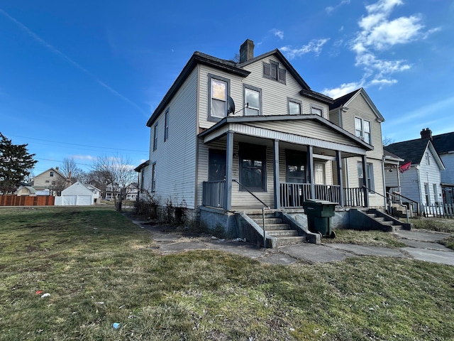 view of front facade with covered porch, a chimney, and a front lawn