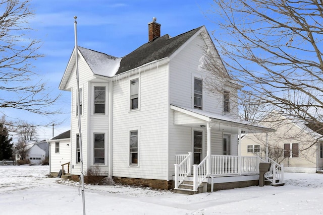 view of snow covered exterior with covered porch and a chimney