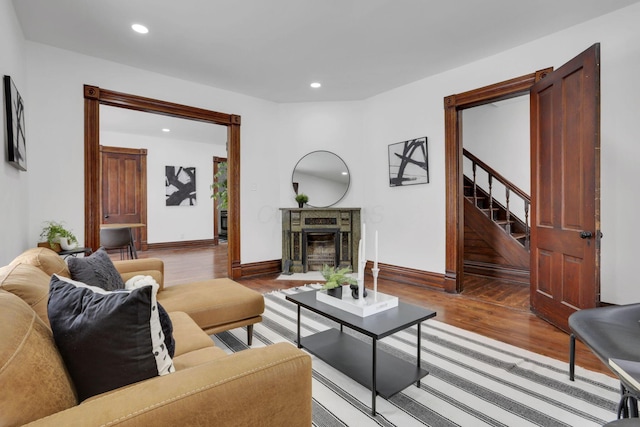 living area with a fireplace, recessed lighting, wood finished floors, baseboards, and stairs