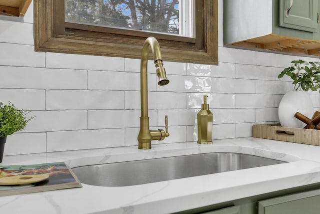 details with a sink, decorative backsplash, light stone countertops, and green cabinetry