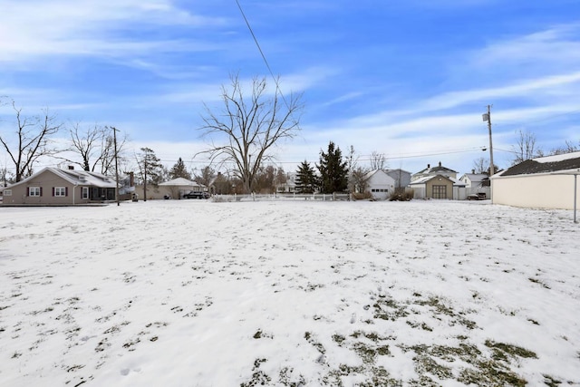 yard layered in snow with a residential view and a detached garage