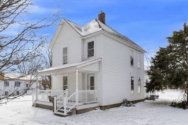 view of front of property featuring a porch, a chimney, and central air condition unit