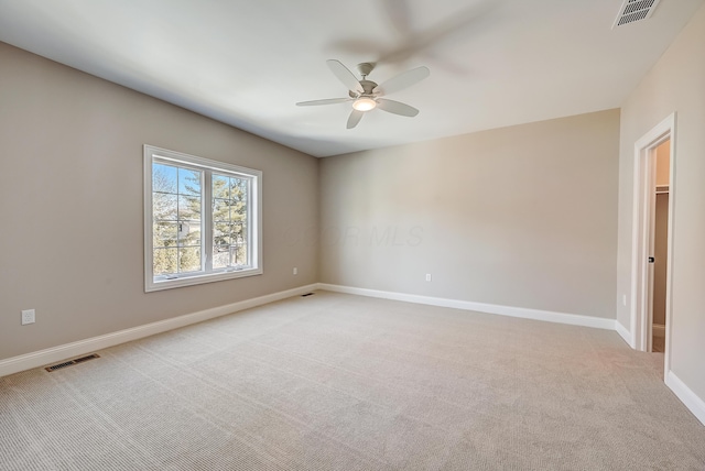 unfurnished room featuring light carpet, a ceiling fan, visible vents, and baseboards