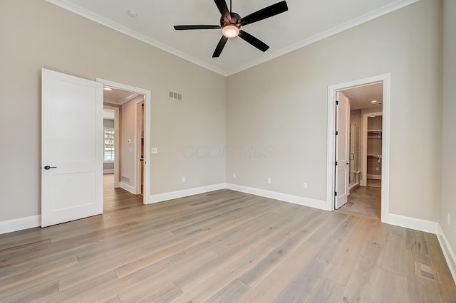 spare room featuring ornamental molding, visible vents, light wood-style flooring, and baseboards