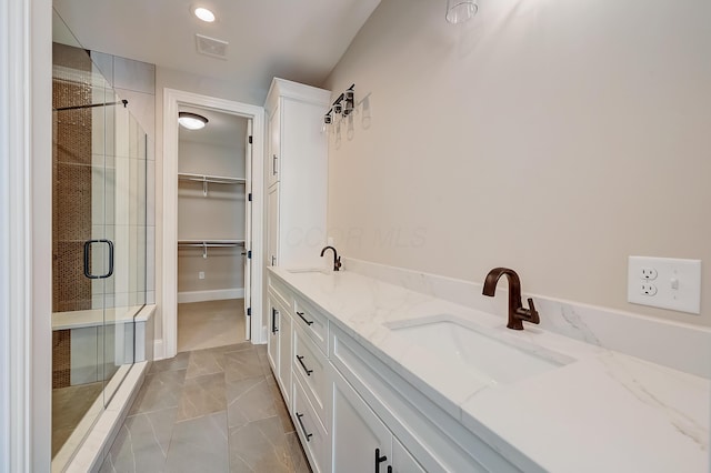 bathroom with double vanity, a stall shower, a sink, and visible vents