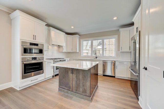 kitchen featuring high end appliances, light countertops, white cabinets, a kitchen island, and premium range hood