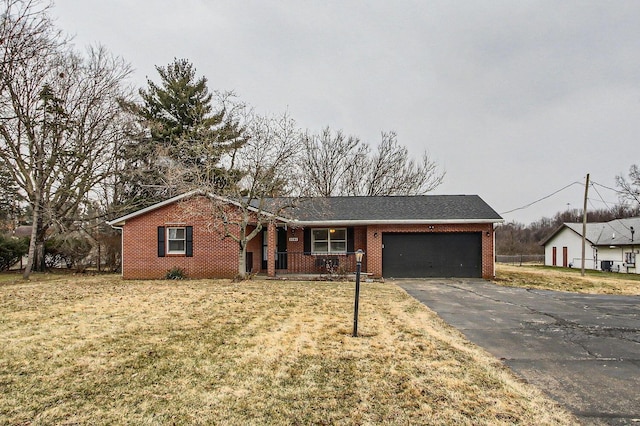 single story home featuring a garage, driveway, brick siding, and a front yard