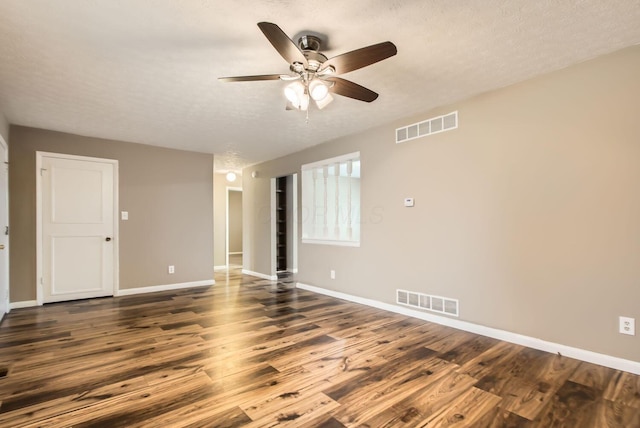 empty room featuring dark wood-type flooring, visible vents, and baseboards