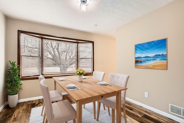 dining room featuring baseboards, visible vents, and wood finished floors