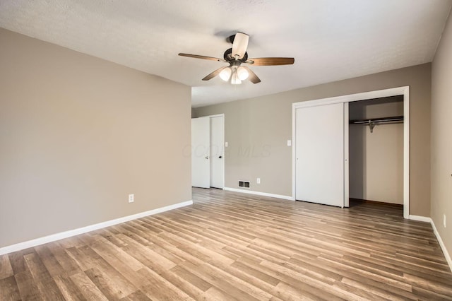 unfurnished bedroom with a ceiling fan, light wood-style flooring, visible vents, and baseboards