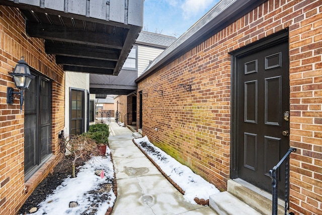 snow covered property entrance with brick siding