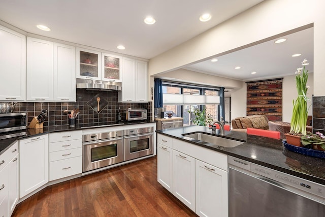 kitchen with white cabinets, glass insert cabinets, stainless steel appliances, under cabinet range hood, and a sink