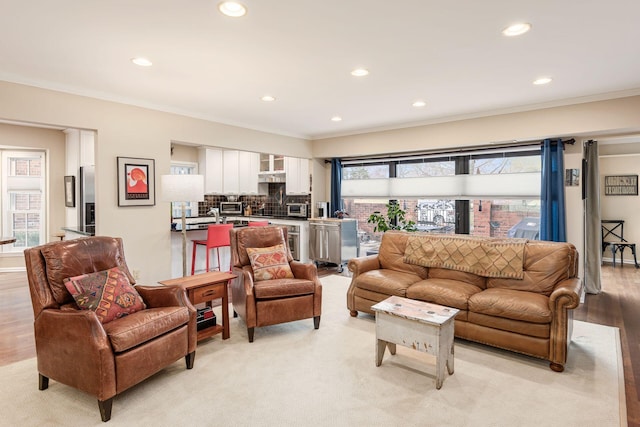 living area featuring light wood finished floors, ornamental molding, and recessed lighting