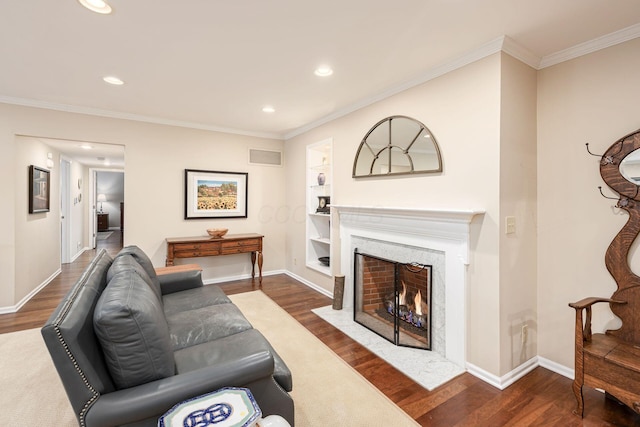 living room featuring ornamental molding, built in shelves, dark wood-type flooring, and visible vents