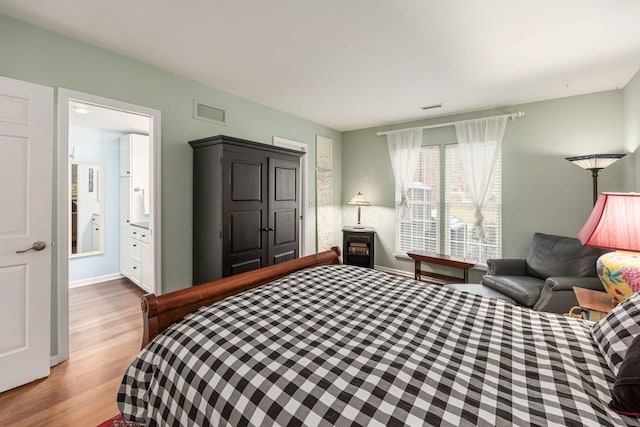 bedroom featuring light wood-style floors, visible vents, and baseboards