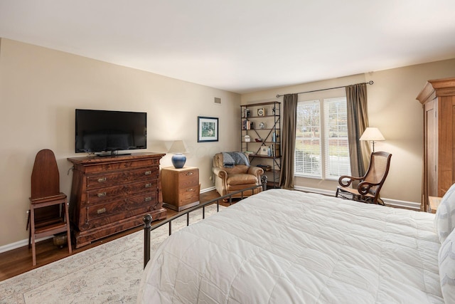 bedroom with visible vents, baseboards, and wood finished floors