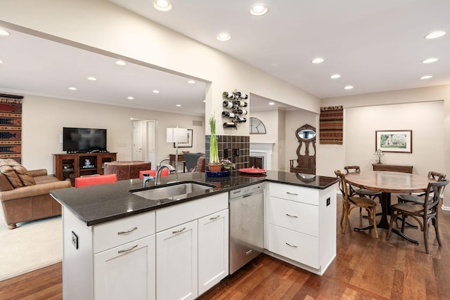 kitchen with open floor plan, stainless steel dishwasher, a sink, and white cabinets