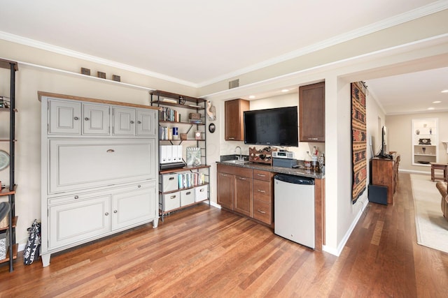 interior space featuring ornamental molding, dark countertops, dishwasher, and light wood-style flooring