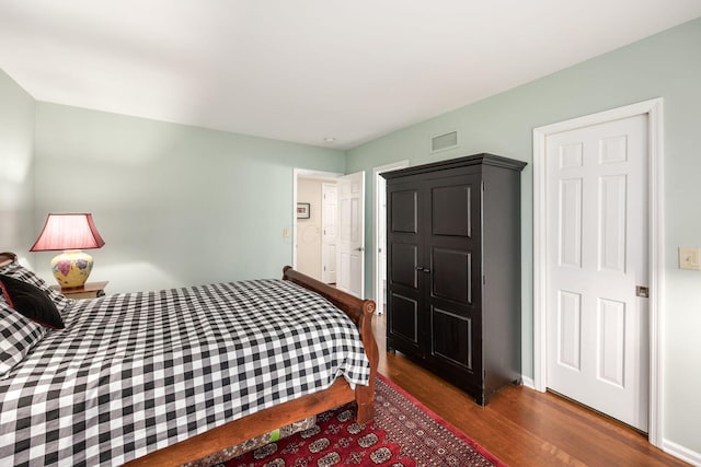 bedroom with baseboards, visible vents, and wood finished floors