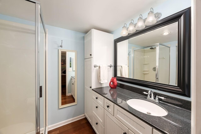 full bathroom featuring a stall shower, baseboards, wood finished floors, and vanity