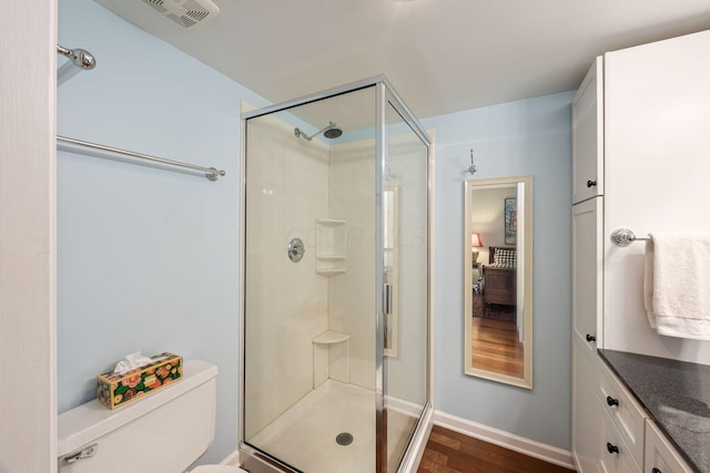 full bath featuring visible vents, toilet, vanity, a shower stall, and wood finished floors