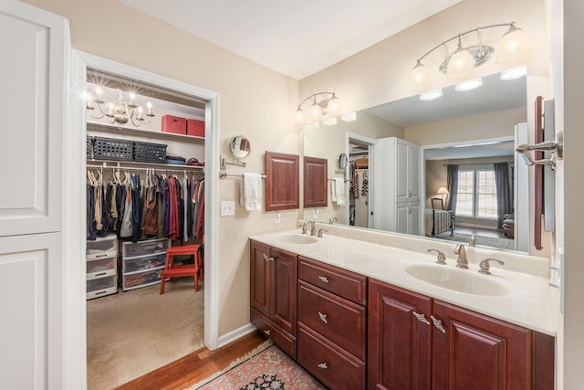 full bath featuring a sink, a spacious closet, baseboards, and double vanity