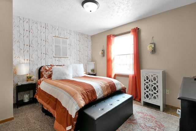 bedroom with an accent wall, carpet flooring, a textured ceiling, baseboards, and wallpapered walls