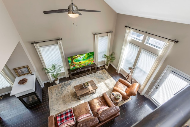 living room with ceiling fan, high vaulted ceiling, dark wood-type flooring, and baseboards