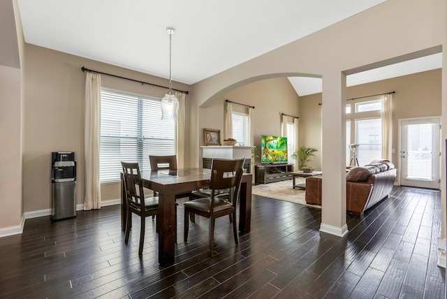 dining space with plenty of natural light, vaulted ceiling, baseboards, and dark wood finished floors