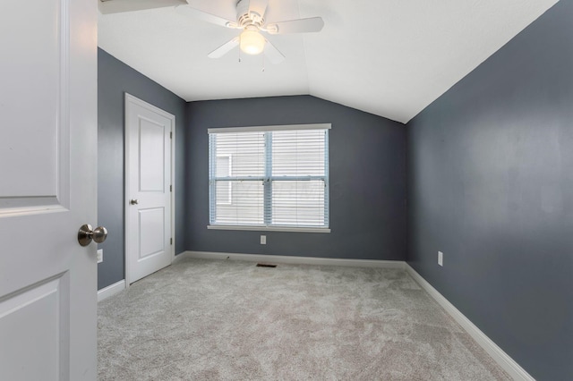 spare room featuring lofted ceiling, baseboards, light carpet, and visible vents