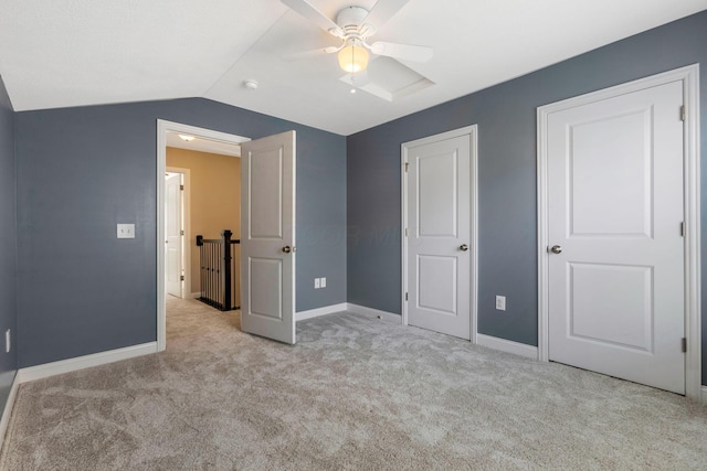 unfurnished bedroom with light carpet, ceiling fan, baseboards, and vaulted ceiling